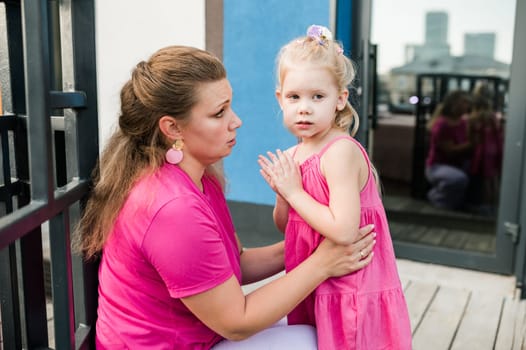 Deaf child with cochlear implant for hearing audio and aid for impairment having fun and laughs with mother outdoor in summer. Sound fitting device to help with communication listening and interaction.