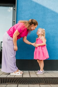 Deaf child with cochlear implant for hearing audio and aid for impairment having fun and laughs with mother outdoor in summer. Sound fitting device to help with communication listening and interaction.