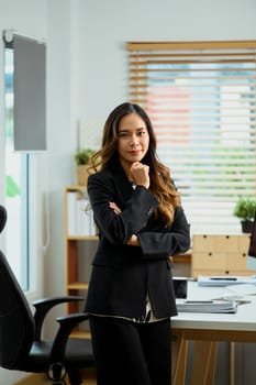Portrait of attractive young businesswoman standing in her office and looking at camera.