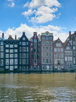 A charming row of buildings silhouettes against the calm waters, creating a picturesque scene of urban architecture meeting natural beauty. Amsterdam Netherlands 21 April 2024