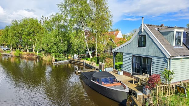 A solitary boat peacefully sits in the calm water, reflecting the sky above with ripples gently lapping at its sides. wooden facades and old houses in Broek in Waterland in the Netherlands