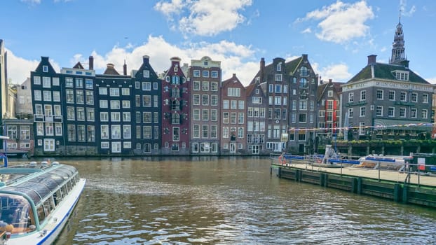 A picturesque scene of a boat gracefully sailing down a river, surrounded by towering city buildings in the background. Amsterdam Netherlands 21 April 2024