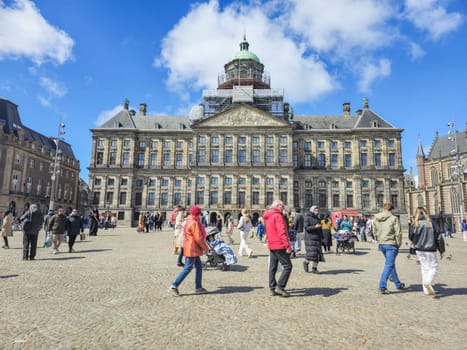 Amsterdam Netherlands 21 April 2024 A diverse group of people walks together in front of an imposing urban building at the Dam Square