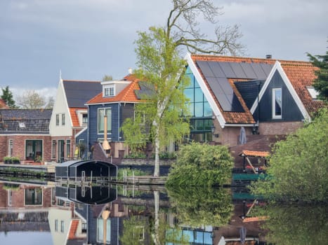 A picturesque scene of a charming row of houses lined up next to a peaceful body of water, creates a tranquil and idyllic setting. wooden facades and old houses in Broek in Waterland in the Netherlands