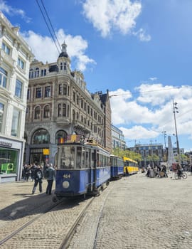 A charming blue and white histroical tram trolley glides gracefully along a bustling city street, adding a touch of nostalgia to the urban landscape. Amsterdam Netherlands 21 April 2024