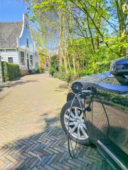 An electric EV car sits serenely in front of a quaint house, blending harmoniously with its surroundings in the Netherlands