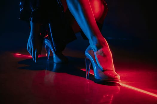Legs of gorgeous woman in high heels shoes under red illumination, laser light, neon club. Projection illusion mapping. High quality photo