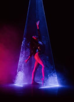 Ballet dancer in pointe under multicolor neon laser light on stage. Woman ballerina posing in dark room. Performance, projection mapping. Interactive installation, Optical visuals. Quality photo