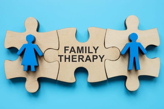 Family therapy concept. Puzzle pieces with figurines and inscription.