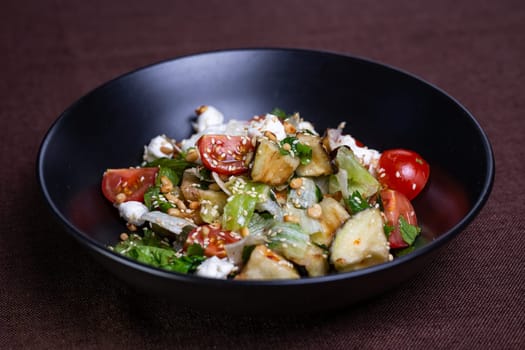 Enjoy a nutritious salad featuring fresh veggies, savory feta, and crunchy pine nuts on a sleek black dish. Perfect for a healthy meal