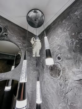 Interior image featuring a cosmonaut lamp, round mirror, and gray wall texture, creating a modern and stylish bathroom.