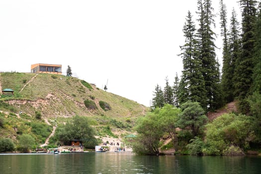 The lake is surrounded by green hills and the water is crystal clear. There is a building on the hill and trees on the shore.