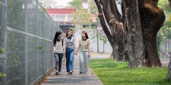 College friends walk to class together. University student in campus talk and have fun outdoors.