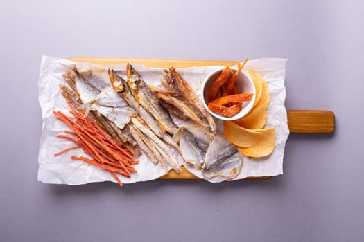 A variety of dehydrated fish, carrots, and pumpkin slices on a white paper over grey background. Isolated on a grey background.