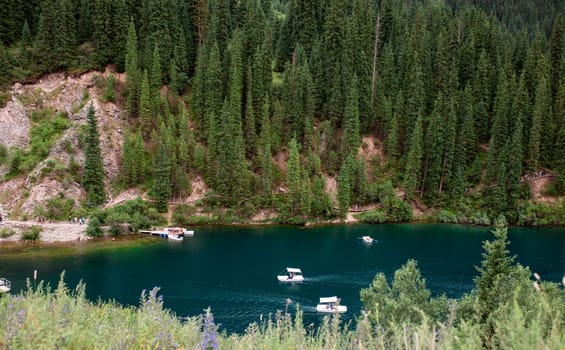 Lake surrounded by hills and mountains, clear blue water with small boats. Beautiful landscape scenery with lake and mountains.