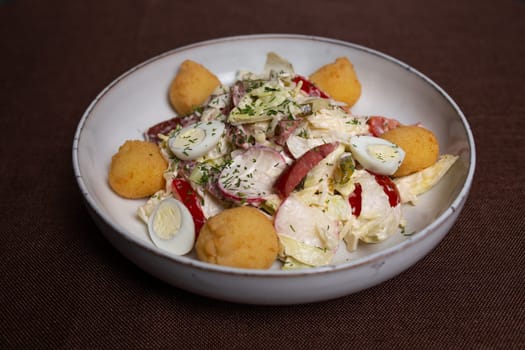 Fresh salad with cherry tomatoes, cucumber, radish, carrot, and lettuce on a white plate, creating a colorful and nutritious dish.