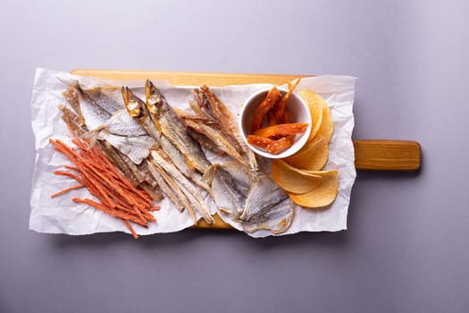 A variety of dehydrated fish, carrots, and pumpkin slices on a white paper over grey background. Isolated on a grey background.