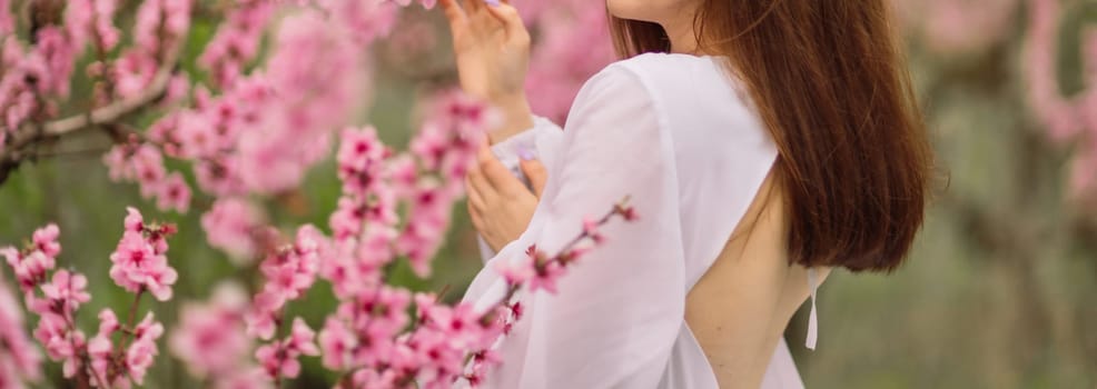 A girl is walking through a field of pink peach flowers. She is wearing a white dress and carrying a basket. The scene is peaceful and serene, with the pink flowers creating a beautiful.