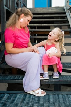 Deaf child with cochlear implant for hearing audio and aid for impairment having fun and laughs with mother outdoor in summer. Sound fitting device to help with communication listening and interaction.