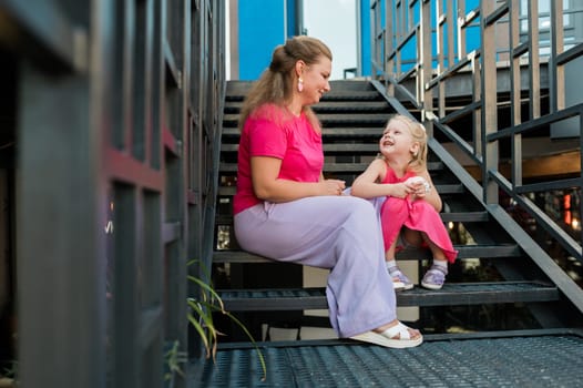 Blonde little girl with cochlear implant playing with her mother outdoor. Hear impairment deaf and health concept. Diversity and inclusion. Copy space.