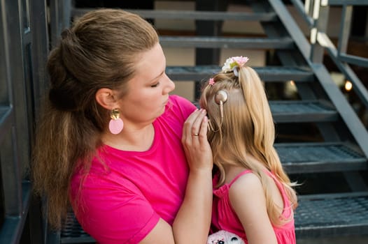 Deaf child with cochlear implant for hearing audio and aid for impairment having fun and laughs with mother outdoor in summer. Sound fitting device to help with communication listening and interaction.