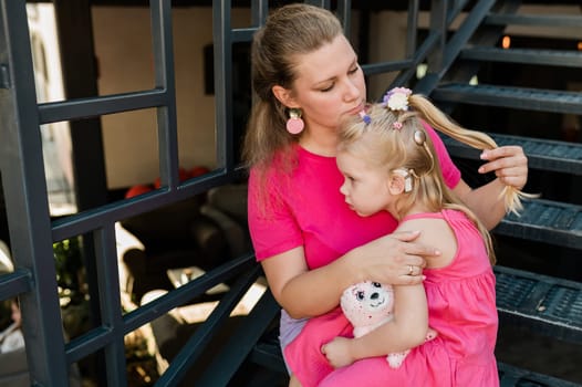 Deaf child with cochlear implant for hearing audio and aid for impairment having fun and laughs with mother outdoor in summer. Sound fitting device to help with communication listening and interaction.