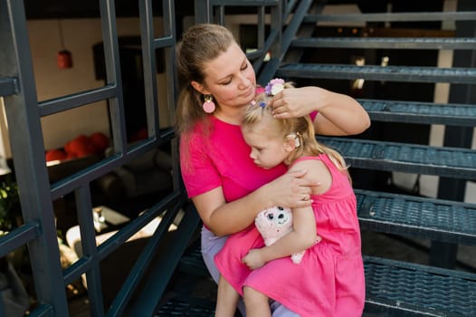 Deaf child with cochlear implant for hearing audio and aid for impairment having fun and laughs with mother outdoor in summer. Sound fitting device to help with communication listening and interaction.