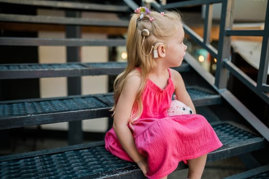 Child girl with hearing aids and cochlear implants having fun outdoor speak and playing. Copy space and empty place for advertising.