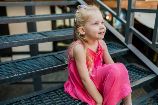 Child with hearing problem and cochlear implant dance in street, deaf kid began to hear. Hearing loss in childhood and treatment concept. Copy space and empty place for text.