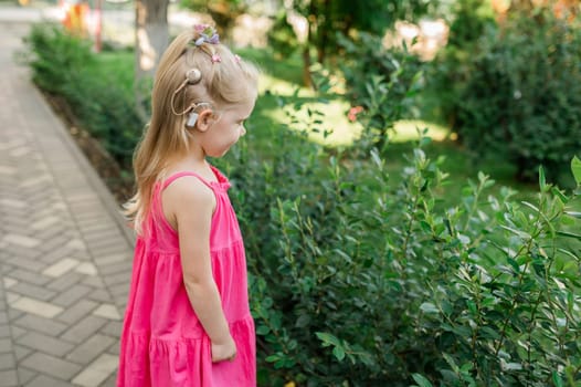 Child with hearing problem and cochlear implant dance in street, deaf kid began to hear. Hearing loss in childhood and treatment concept. Copy space and empty place for text.