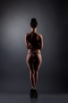 Rear view on topless slim woman in black thong panties