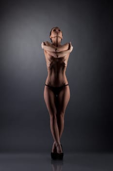 Studio photo of skinny girl posing topless hugging herself