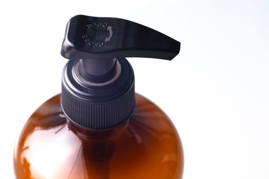 Liquid soap dispenser button, transparent plastic bottle, top view close-up macro view, isolated on white background