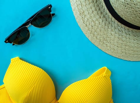 Summer vacation. Swimsuit, sunglasses and a hat on a blue background. Background for advertising.