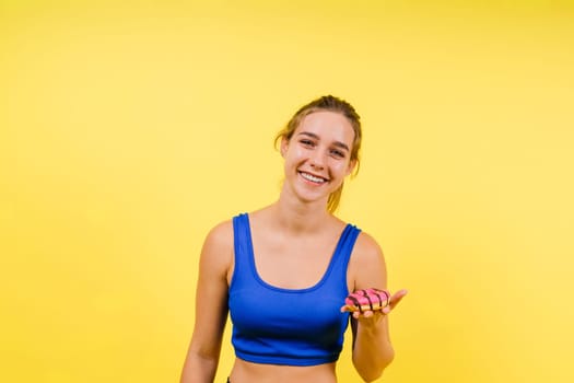 Young cute sport woman eating donut cake in studio background