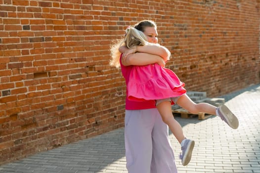 Deaf child with cochlear implant for hearing audio and aid for impairment having fun and laughs with mother outdoor in summer. Sound fitting device to help with communication listening and interaction.