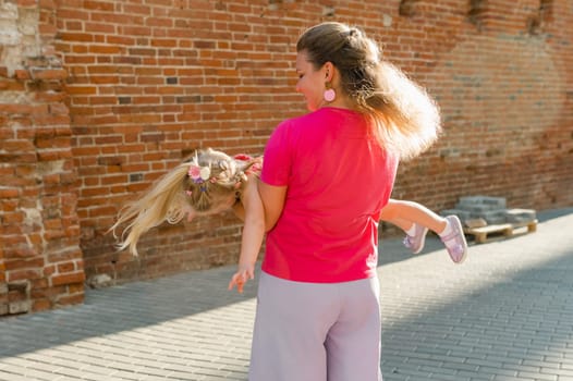 Deaf child with cochlear implant for hearing audio and aid for impairment having fun and laughs with mother outdoor in summer. Sound fitting device to help with communication listening and interaction.