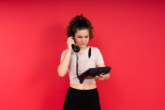 Portrait of pretty person arms hold vintage handset doubtful face isolated on a red color background