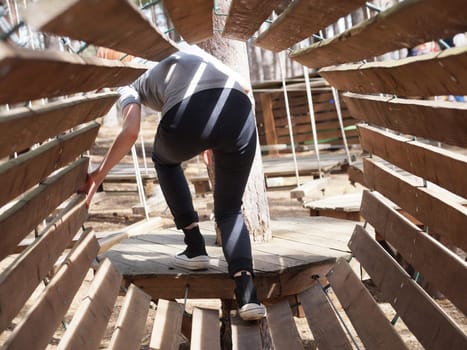 girl coming out of a wooden tunnel obstacle course outdoors.