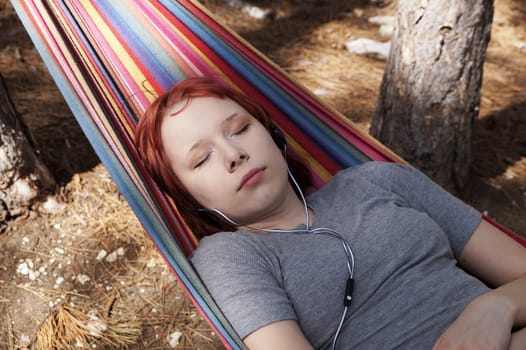 teenage girl sleeping in a hammock outdoors.