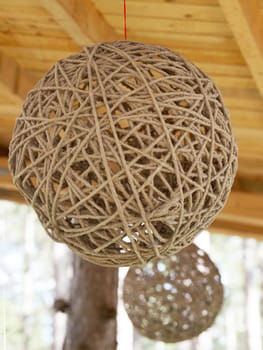 hanging spherical twine lampshade under wooden structure close-up
