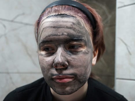 portrait of a girl with a charcoal face mask close-up.