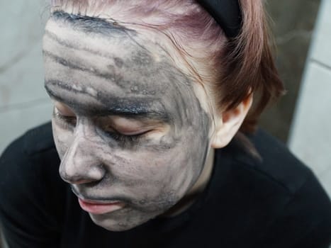 face of a teenage girl with a cleansing mud mask close-up