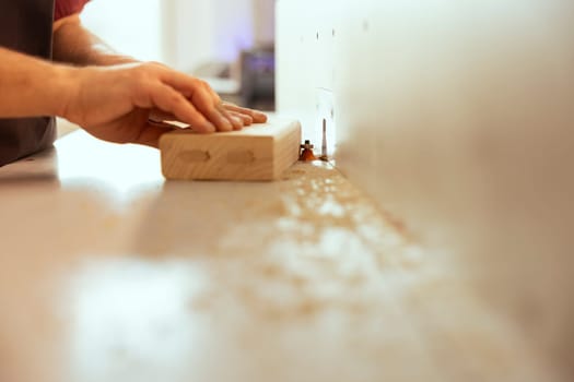 Cabinetmaker using wood shaper machinery to finish precise cutting on wood piece in studio. Woodworking professional in joinery shop using spindle moulder gear to do assembling