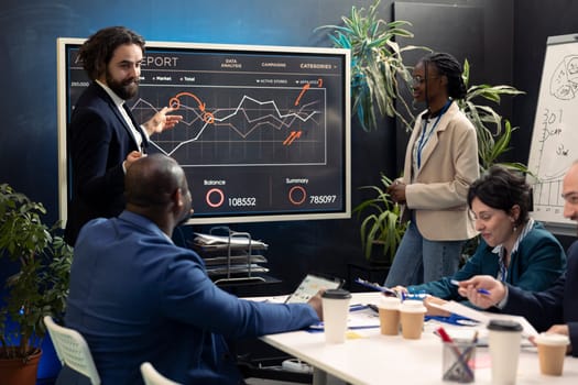 Marketing team assembling in an information sharing meeting to review updates on regulatory changes or industry standards. Business employees reviewing data analysis infographics.