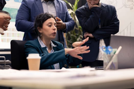 Dissatisfied angry supervisor reading the development project on laptop, being displeased with her team and their progress. Stressed disappointed manager getting angry with her staff.