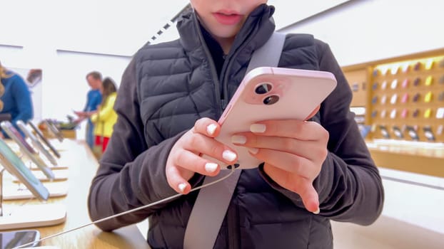 Denver, Colorado, USA-March 23, 2024-curious little girl examines the latest iPhone models on display at the Apple Store located in Park Meadows Mall, showcasing a youthful interest in technology.