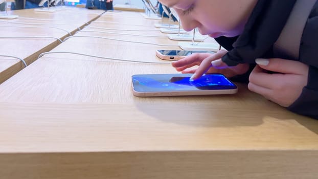 Denver, Colorado, USA-March 23, 2024-curious little girl examines the latest iPhone models on display at the Apple Store located in Park Meadows Mall, showcasing a youthful interest in technology.