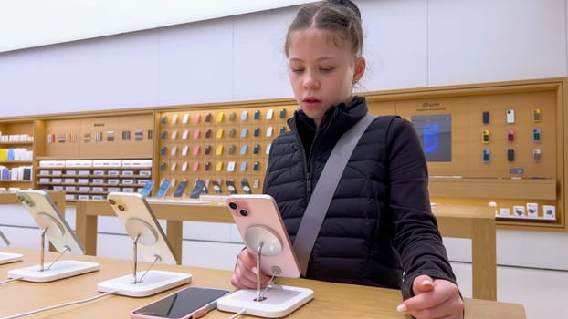 Denver, Colorado, USA-March 23, 2024-curious little girl examines the latest iPhone models on display at the Apple Store located in Park Meadows Mall, showcasing a youthful interest in technology.
