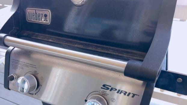 Denver, Colorado, USA-March 23, 2024-Up-close view of a Weber grill in use, with someone’s hands actively managing the food being cooked, showcasing the enjoyment of outdoor grilling.